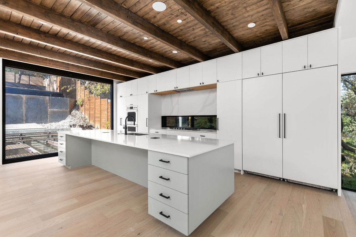 1603 Chelsea Lane, Unit 3 Austin, TX 78704 - Photo 4 of 40 Kitchen featuring light wood finished floors, white cabinets, a large island, a wood ceiling with exposed beams, and built in desk