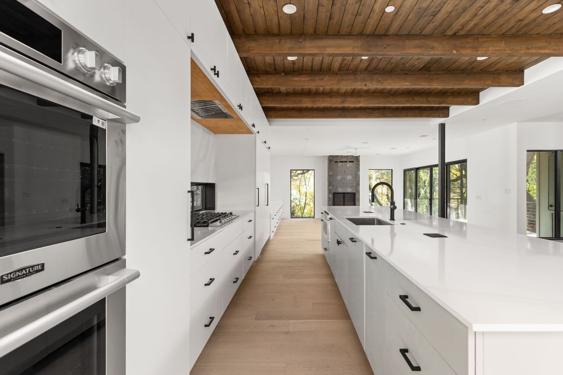 1603 Chelsea Lane, Unit 3 Austin, TX 78704 - Photo 7 of 40 Kitchen featuring white cabinetry, stainless steel appliances, a spacious island, a wood ceiling with exposed beams, and recessed lighting