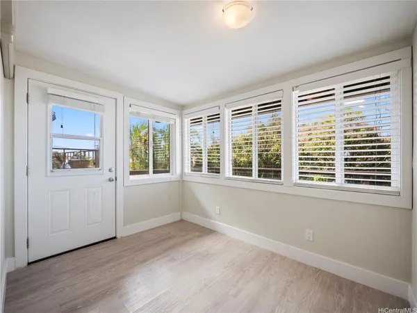 a view of an empty room with wooden floor and a window