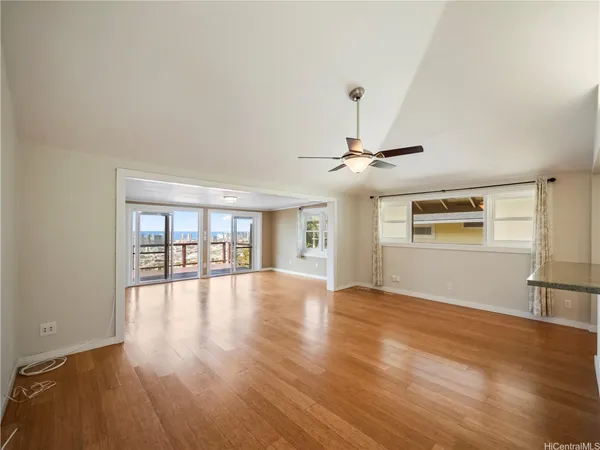 an empty room with wooden floor chandelier fan and windows