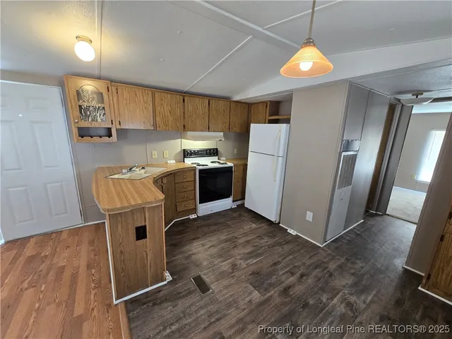 a kitchen with granite countertop a refrigerator a stove top oven a sink dishwasher and white cabinets with wooden floor