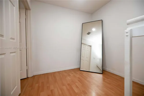 a view of an empty room with wooden floor and closet