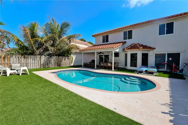 a view of a white house with a swimming pool and a chairs