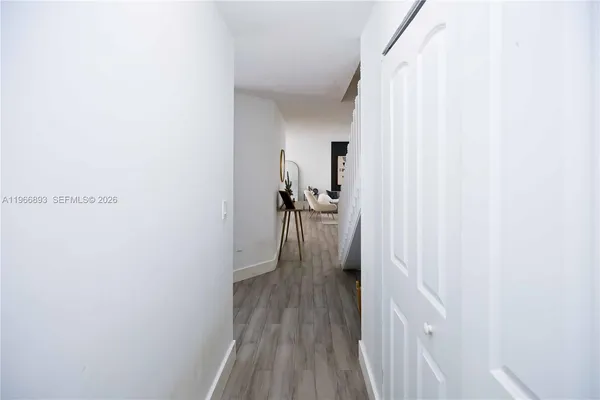 a view of a hallway with wooden floor and a bathroom
