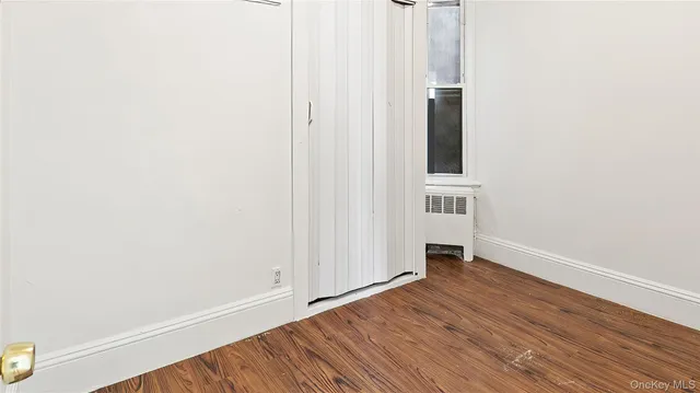 a view of an empty room with wooden floor and closet