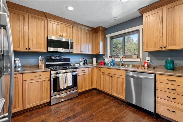 a kitchen with stainless steel appliances granite countertop a sink a stove and cabinets