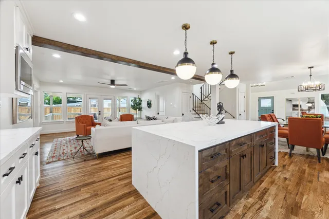 a large kitchen with a counter space a sink appliances and living room view