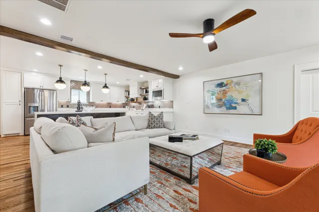 a living room with furniture kitchen view and a chandelier