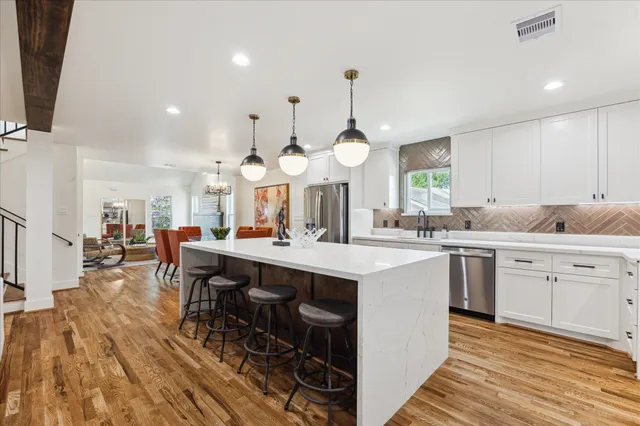 a large kitchen with cabinets a sink a stove and chairs with wooden floor