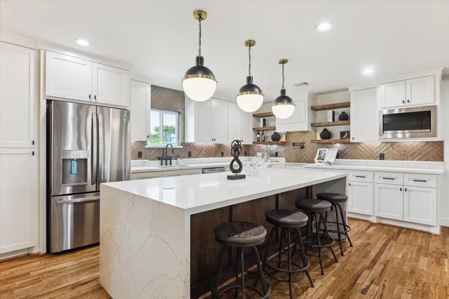 a kitchen with stainless steel appliances a sink a stove a refrigerator and cabinets