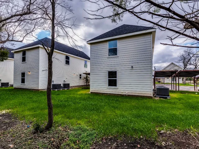 a view of a white house next to a yard with big trees