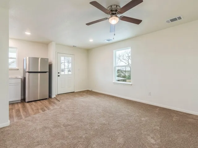 an empty room with windows and ceiling fan