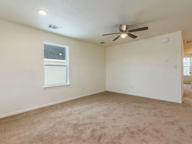 an empty room with a window and a fan