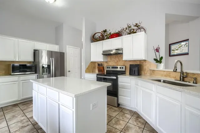 a kitchen with white cabinets and sink