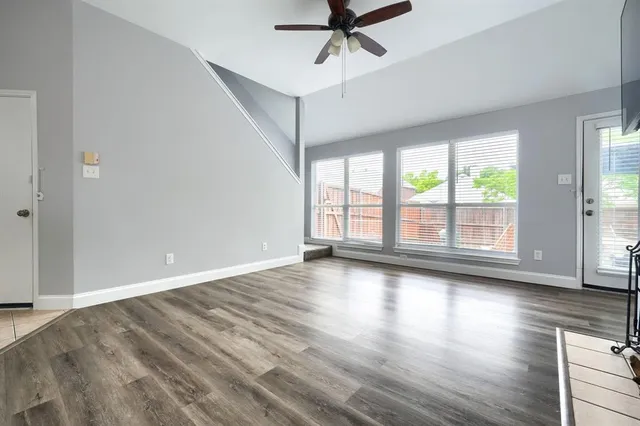 an empty room with wooden floor fan and windows