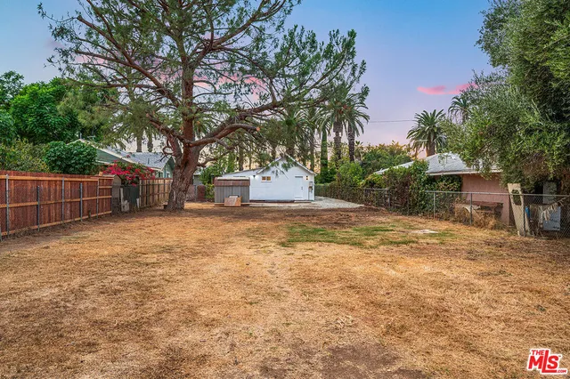 a backyard of a house with large trees and outdoor seating