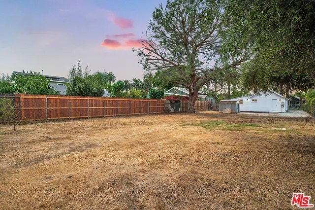 a view of yard with tree and wooden fence