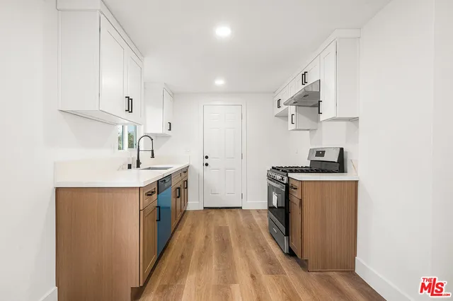 a kitchen with a sink stove top oven and white cabinets