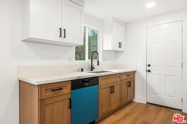 a kitchen with a sink cabinets and wooden floor