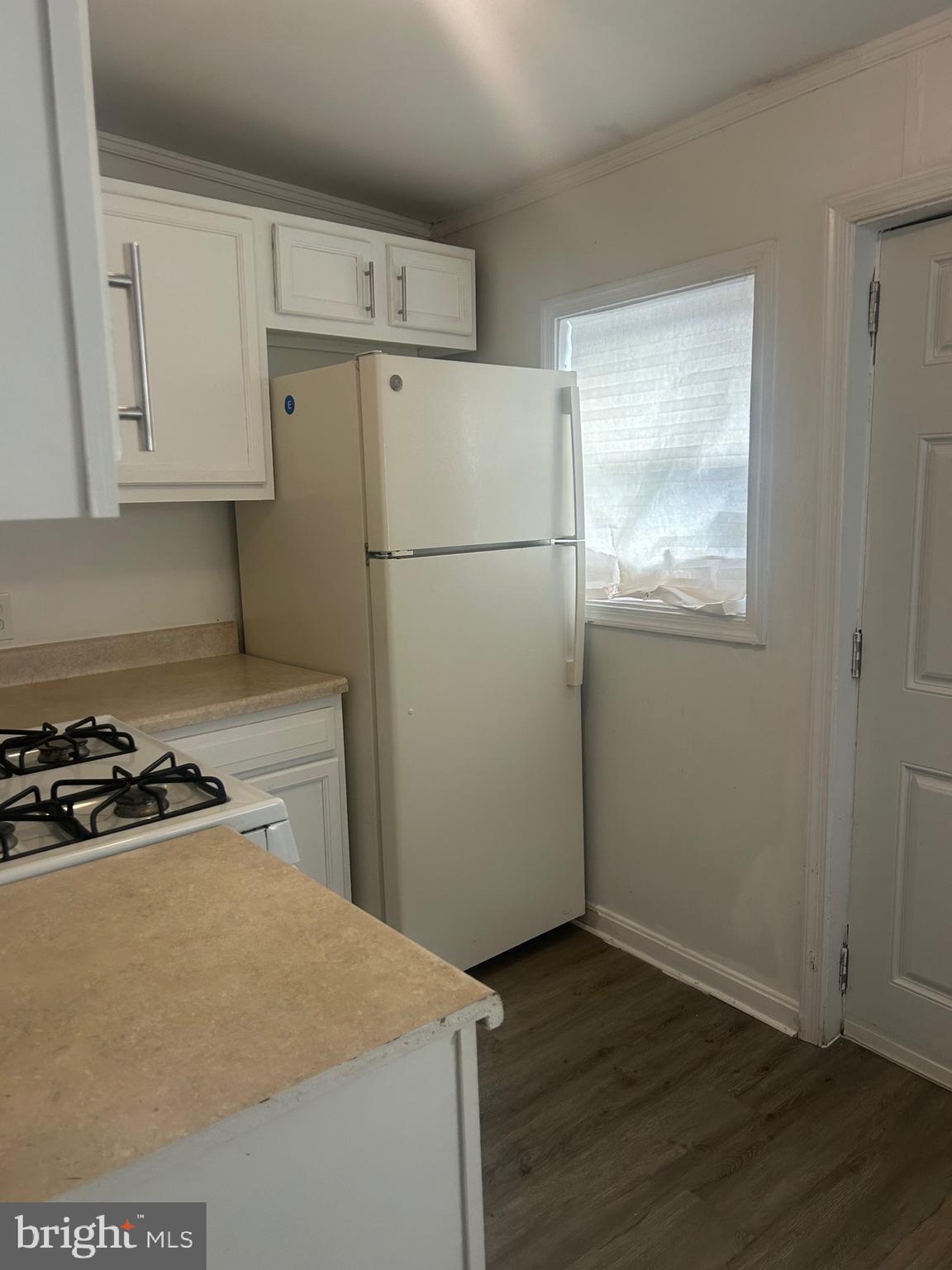 2136 North Fulton Avenue, Unit 3 Baltimore, MD 21217 - Photo 2 of 8 a kitchen with a refrigerator a stove a wooden floor and cabinets