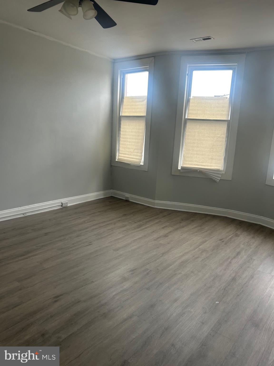 2136 North Fulton Avenue, Unit 3 Baltimore, MD 21217 - Photo 5 of 8 an empty room with wooden floor and windows