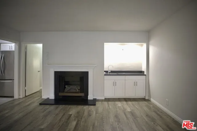a view of an empty room with wooden floor and a fireplace