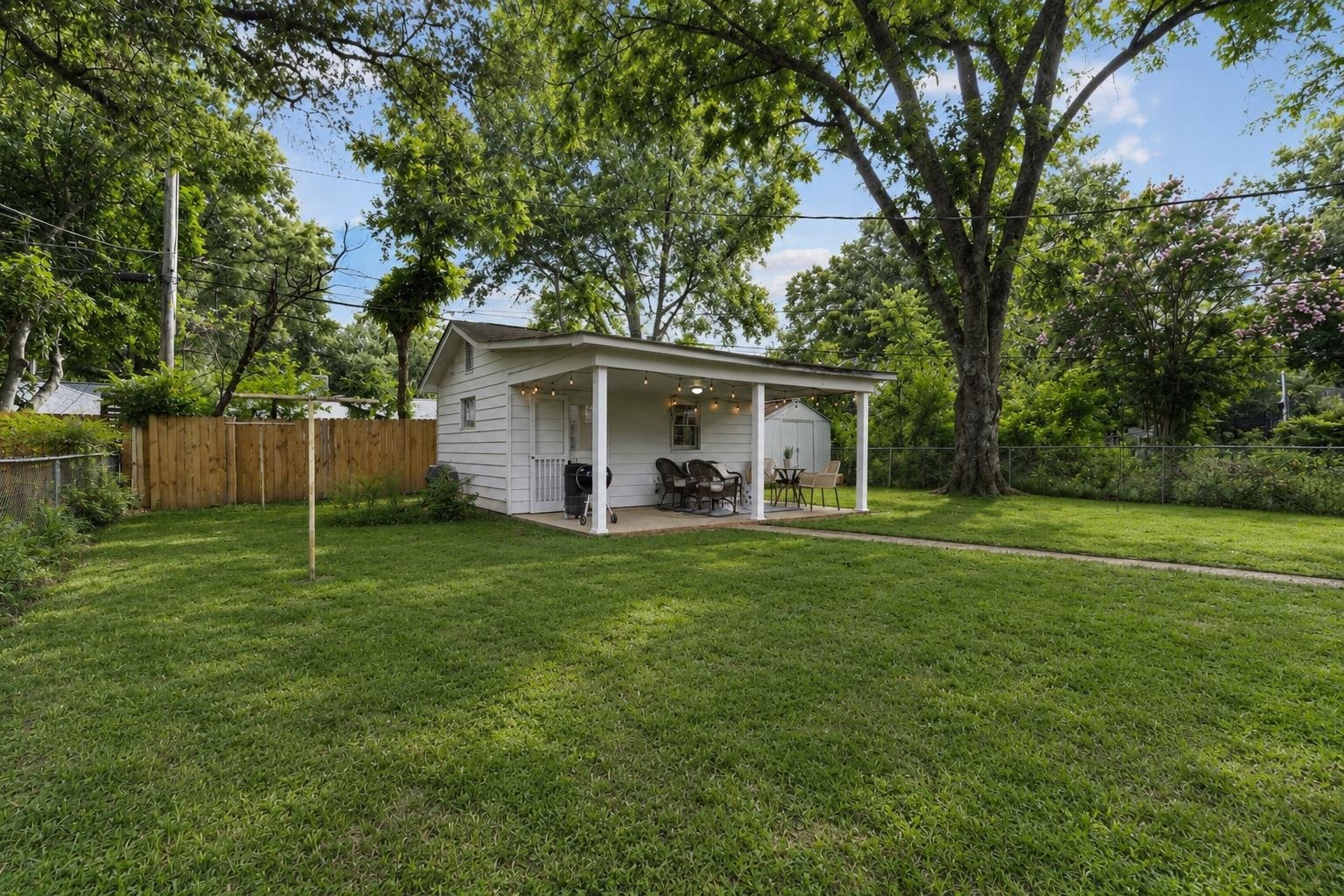4491 Garnett Road Memphis, TN 38117 - Photo 25 of 32 Expansive backyard featuring a covered patio, a detached storage shed, a wood privacy fence, and mature trees