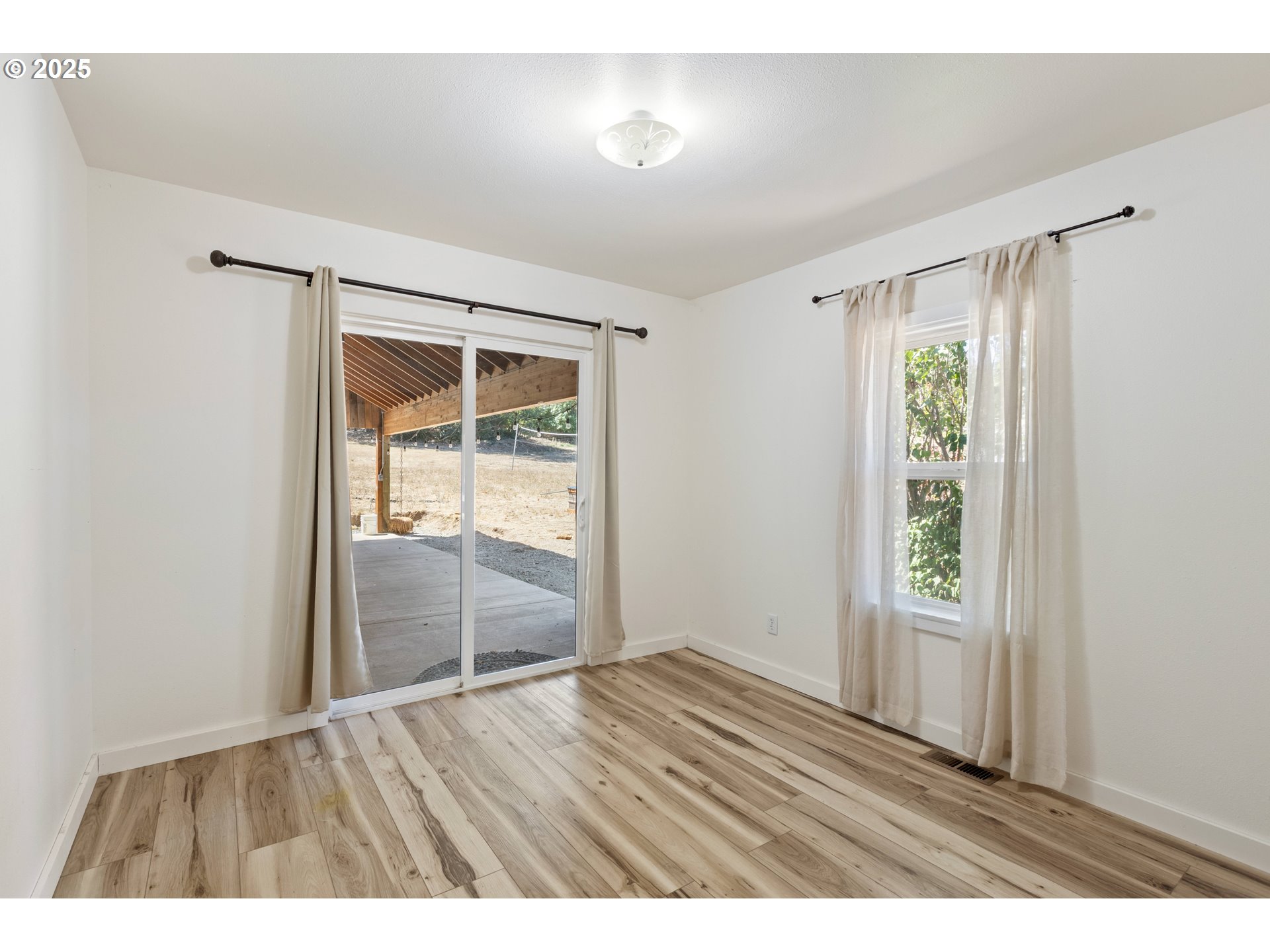 187 Hackett Lane Riddle, OR 97469 - Photo 16 of 48 an empty room with wooden floor and windows