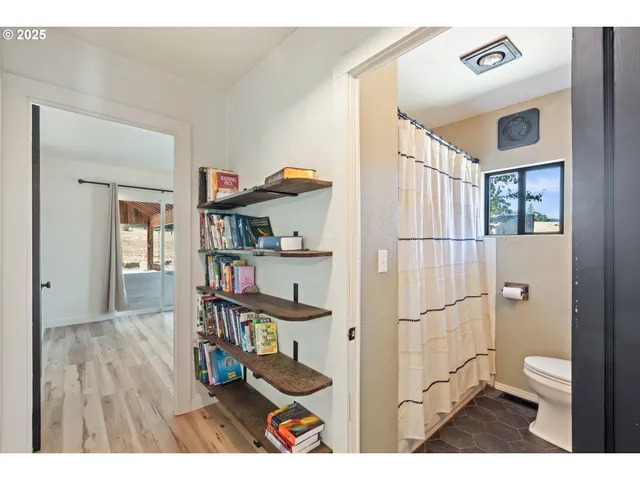 a living room with a wooden floor and a book shelf