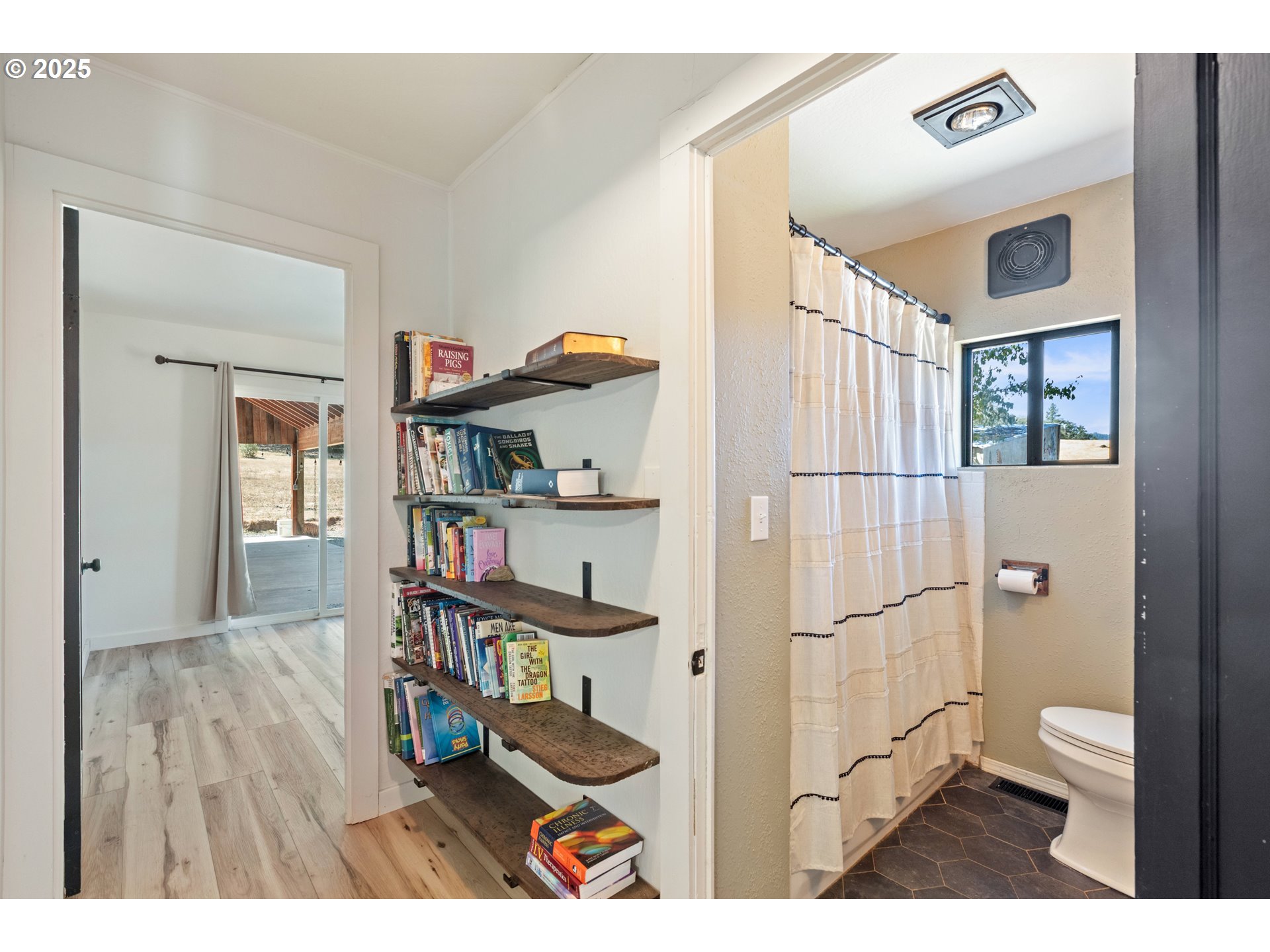 187 Hackett Lane Riddle, OR 97469 - Photo 20 of 48 a living room with a wooden floor and a book shelf