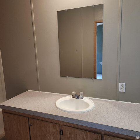 3760 Gold Ridge Drive, Unit 82 Magna, UT 84044 - Photo 22 of 29 Bathroom vanity featuring a built-in sink, wood-finish cabinetry, and a wall-mounted mirror