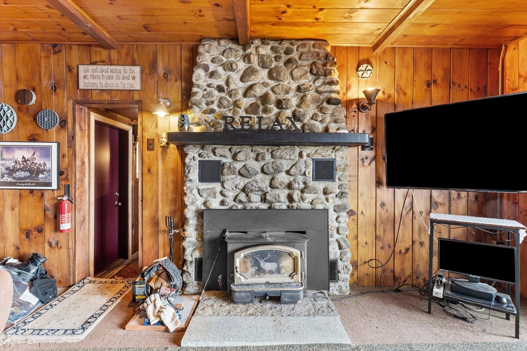 110 Stodge Meadow Road Ashburnham, MA 01430 - Photo 7 of 27 a living room with a fireplace a flat screen tv and a table