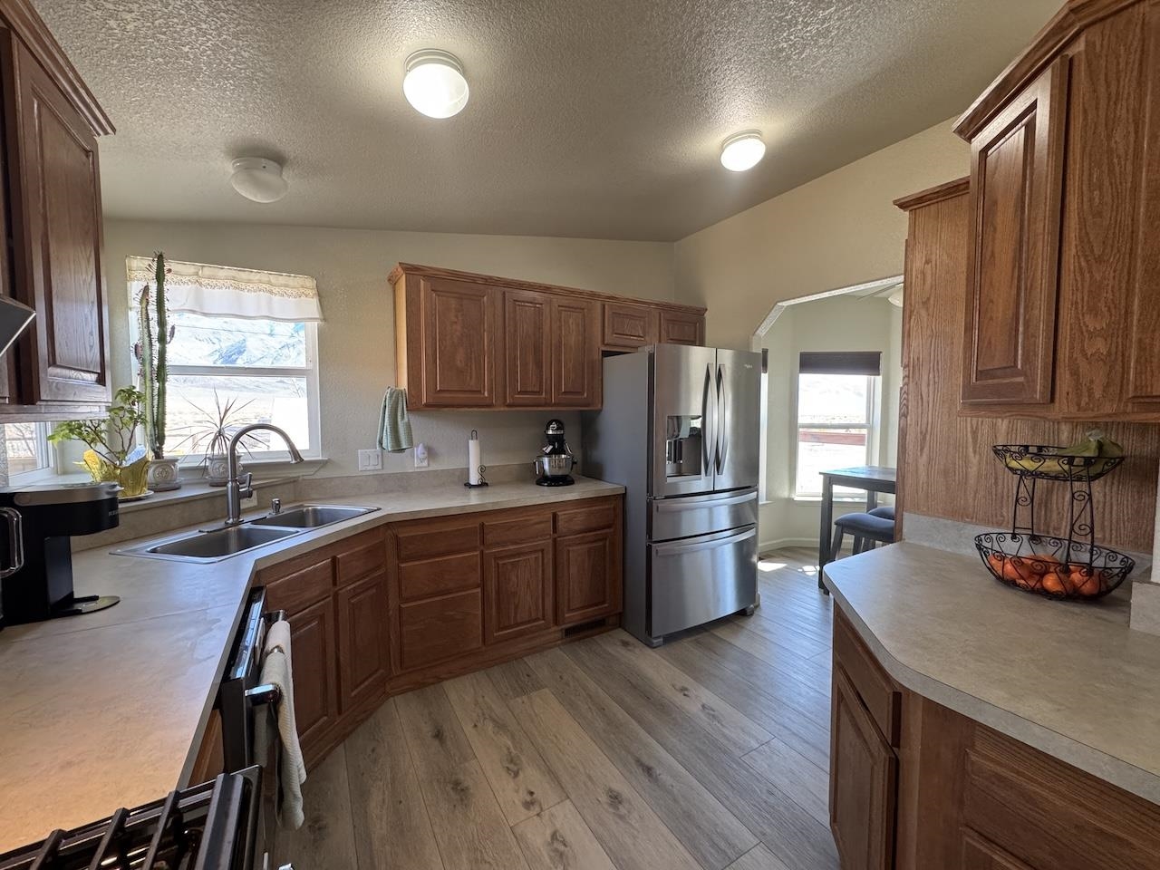 352 Wofford Road, Unit 4 Bishop, CA 93514 - Photo 7 of 40 Kitchen featuring stainless steel refrigerator with ice dispenser, light countertops, arched walkways, wood finish cabinets, and light wood-style flooring