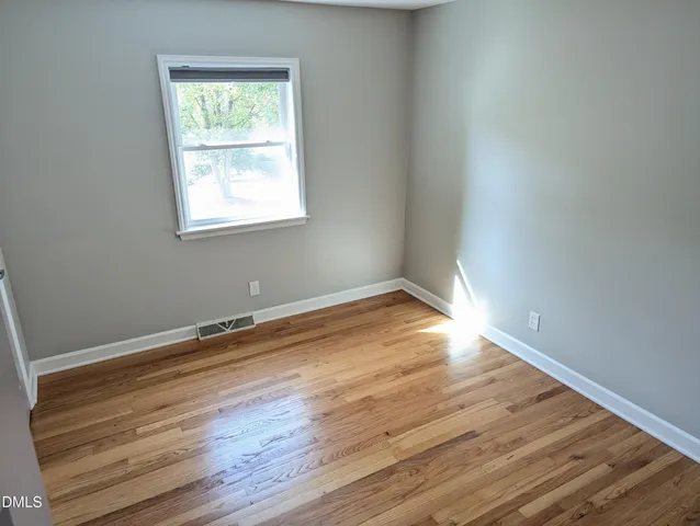 an empty room with wooden floor and a window