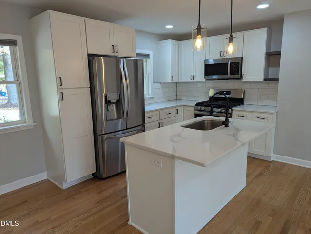 a kitchen with a refrigerator a microwave a sink and wooden floor