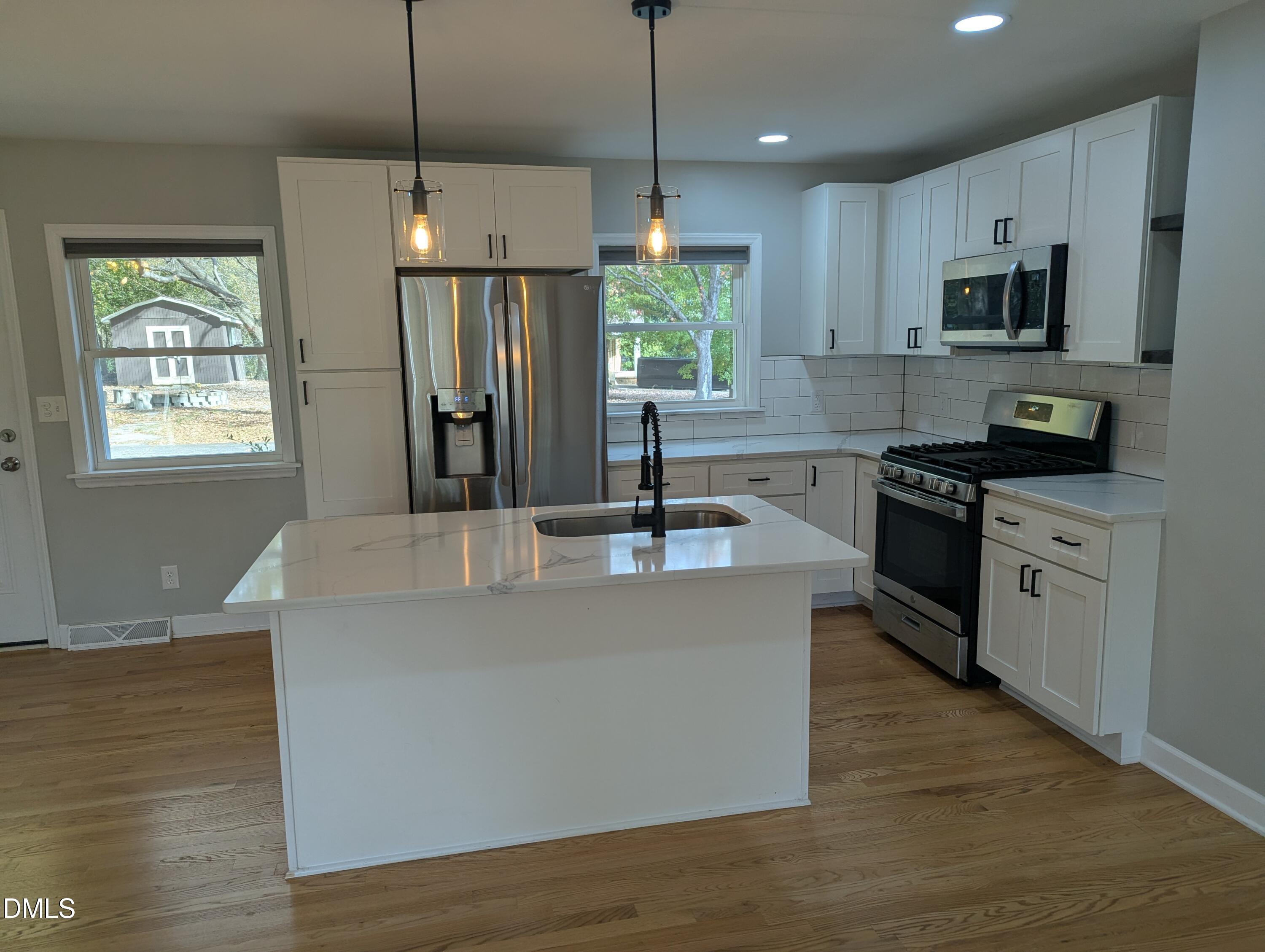 4011 Garrett Road Durham, NC 27707 - Photo 6 of 21 a kitchen with stainless steel appliances granite countertop a sink a stove a refrigerator cabinets and wooden floor