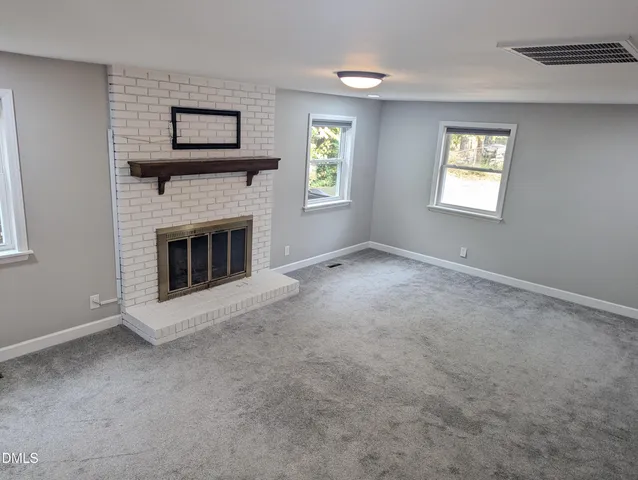 a view of an empty room with window and fireplace