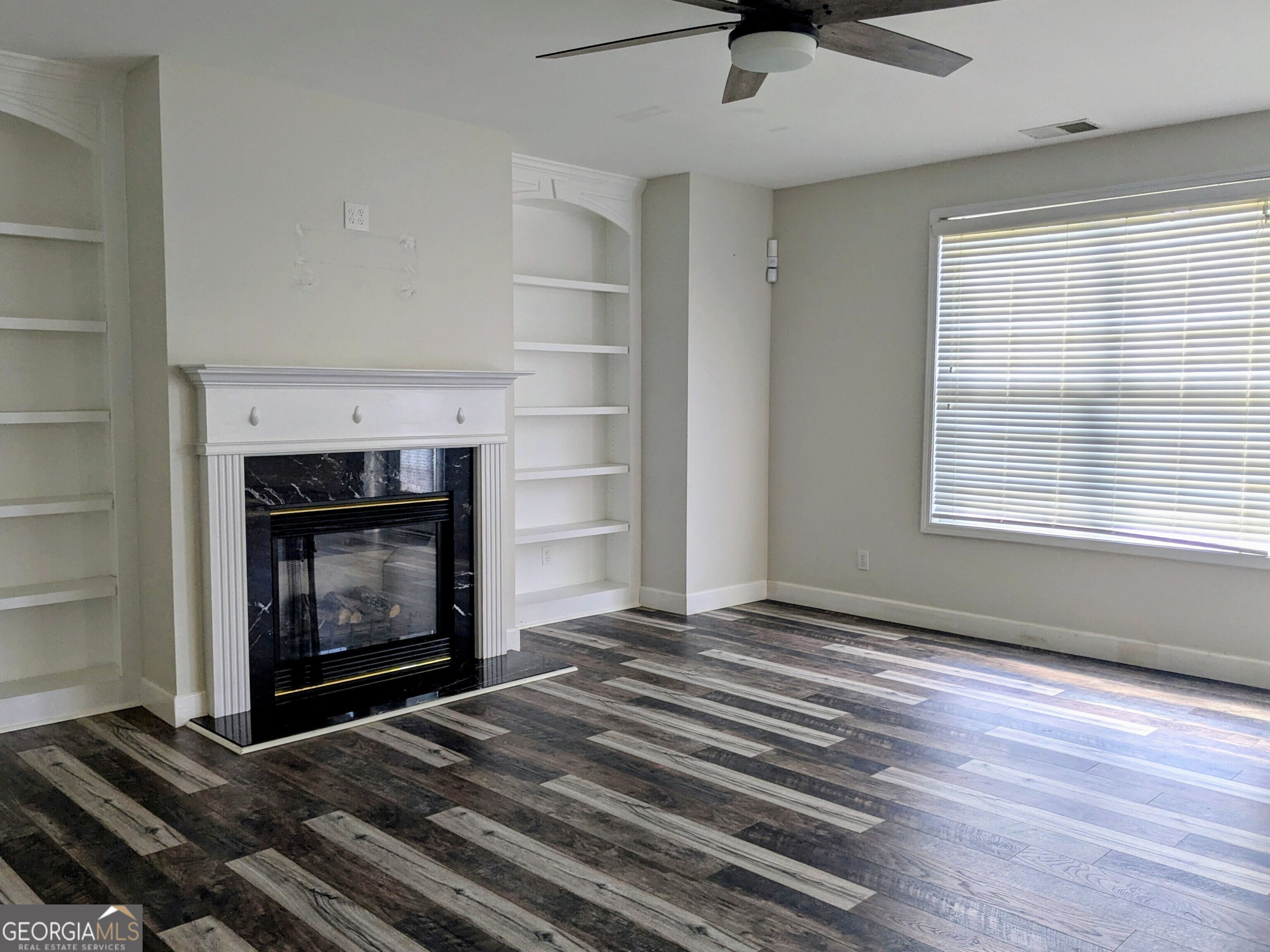 137 Village Green Circle Tyrone, GA 30290 - Photo 11 of 30 a view of an empty room with wooden floor fireplace and a window