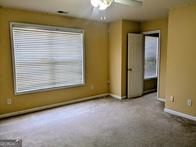 an empty room with a window and chandelier fan