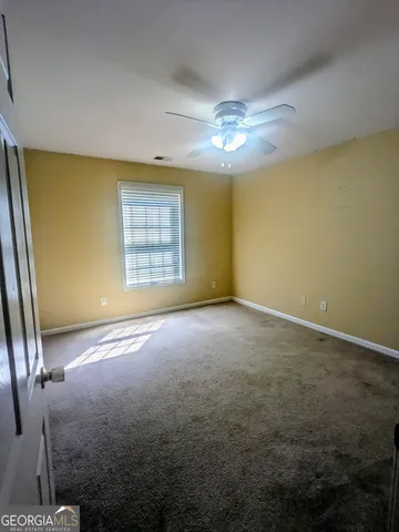 an empty room with windows and chandelier fan