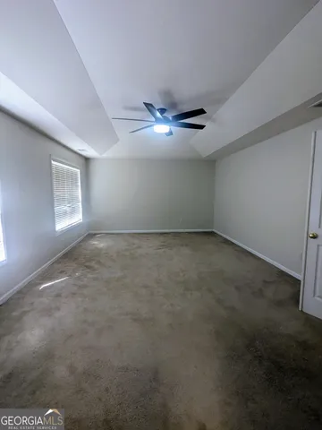 an empty room with windows and fan