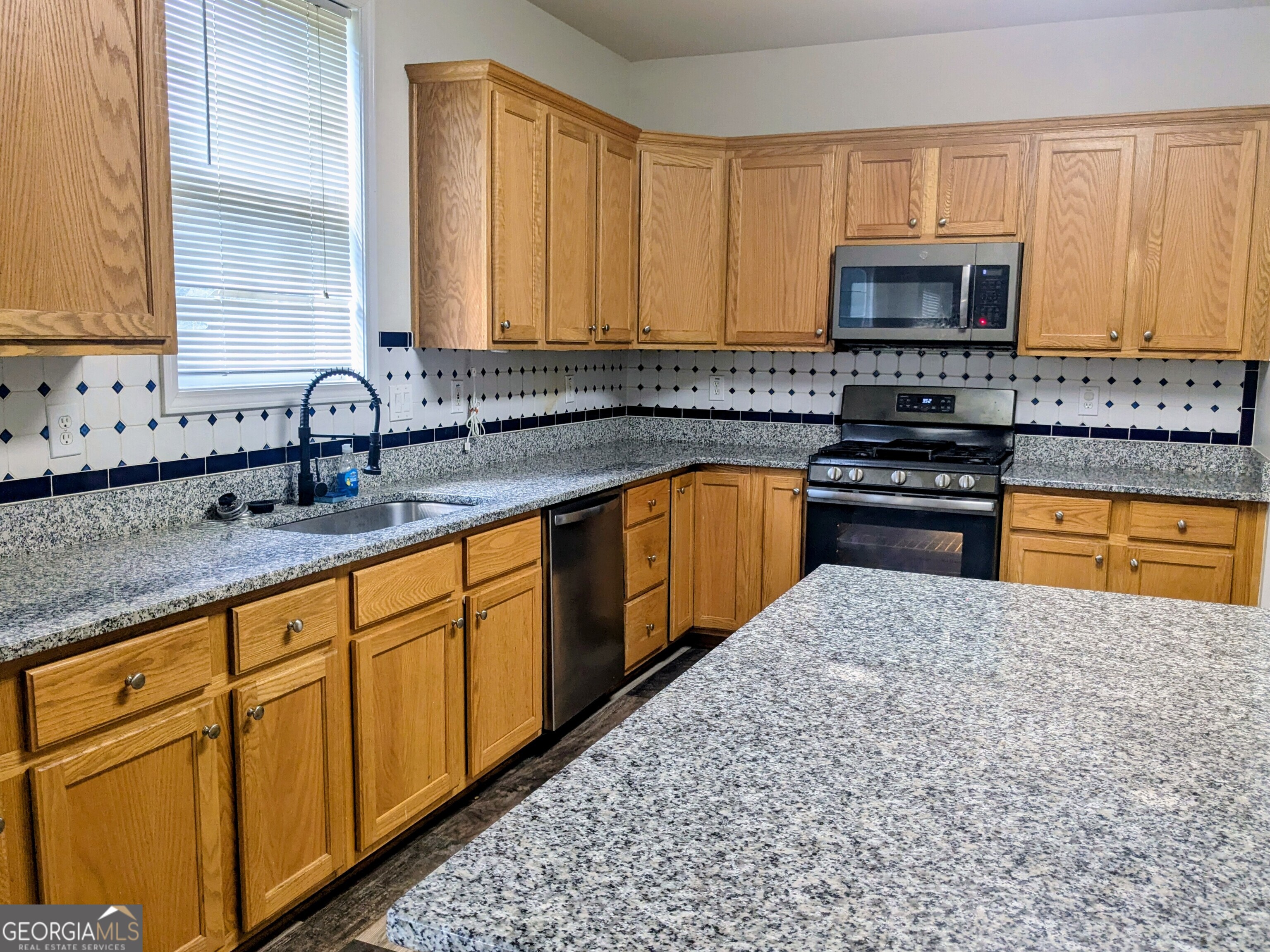 137 Village Green Circle Tyrone, GA 30290 - Photo 7 of 30 a kitchen with stainless steel appliances granite countertop a sink stove and microwave