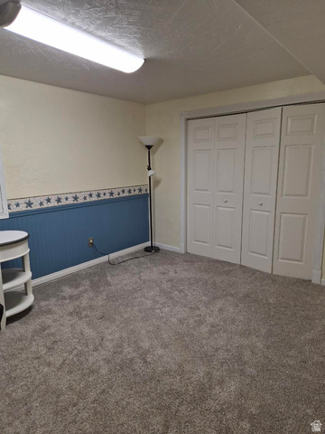 1697 West 2450 Vernal, UT 84078 - Photo 18 of 36 Unfurnished bedroom featuring a wainscoted wall, carpet, a textured ceiling, and a closet