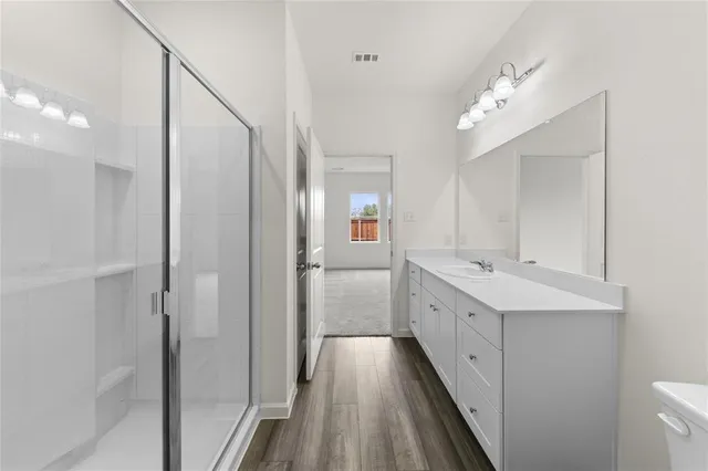 a spacious bathroom with a double vanity sink a toilet and a mirror