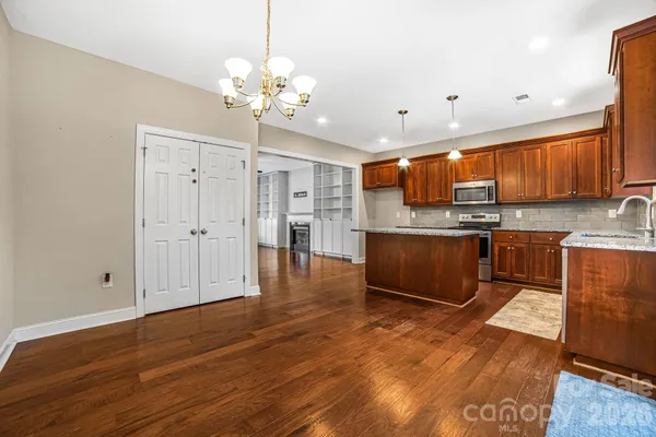 a large kitchen with stainless steel appliances granite countertop a stove a sink dishwasher and a refrigerator with wooden floor