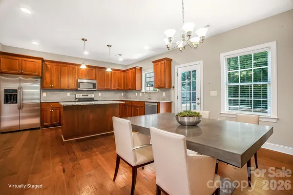 a kitchen with kitchen island a dining table chairs and stainless steel appliances