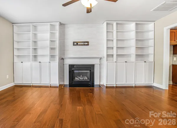 a view of a livingroom with wooden floor a fireplace and window