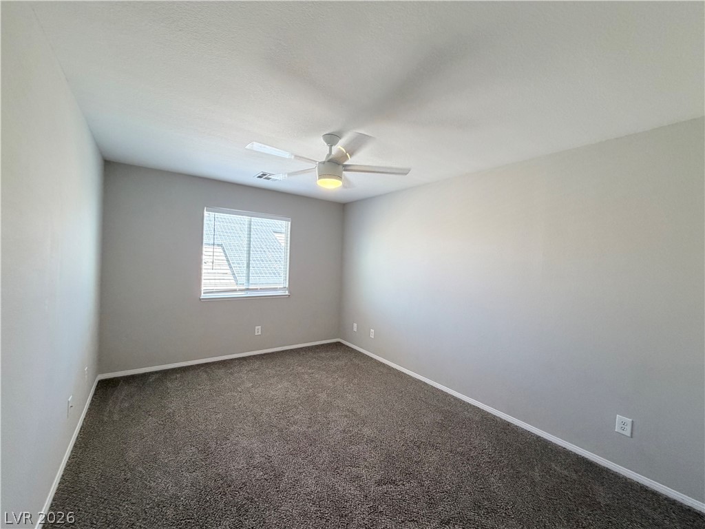 6116 Rabbit Track Street Las Vegas, NV 89130 - Photo 18 of 28 A well-lit bedroom features plush carpeting and a ceiling fan for comfort.