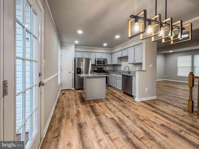 a kitchen with kitchen island granite countertop a sink cabinets and stainless steel appliances