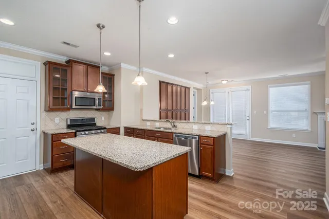 a kitchen with a stove kitchen island a sink and wooden floor